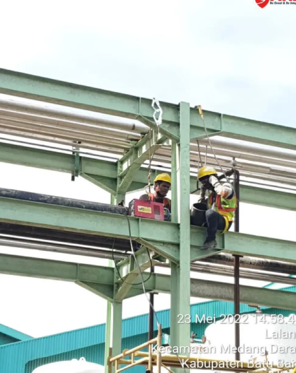 Teknisi dengan harness bekerja pada pipe rack foam fire fighting